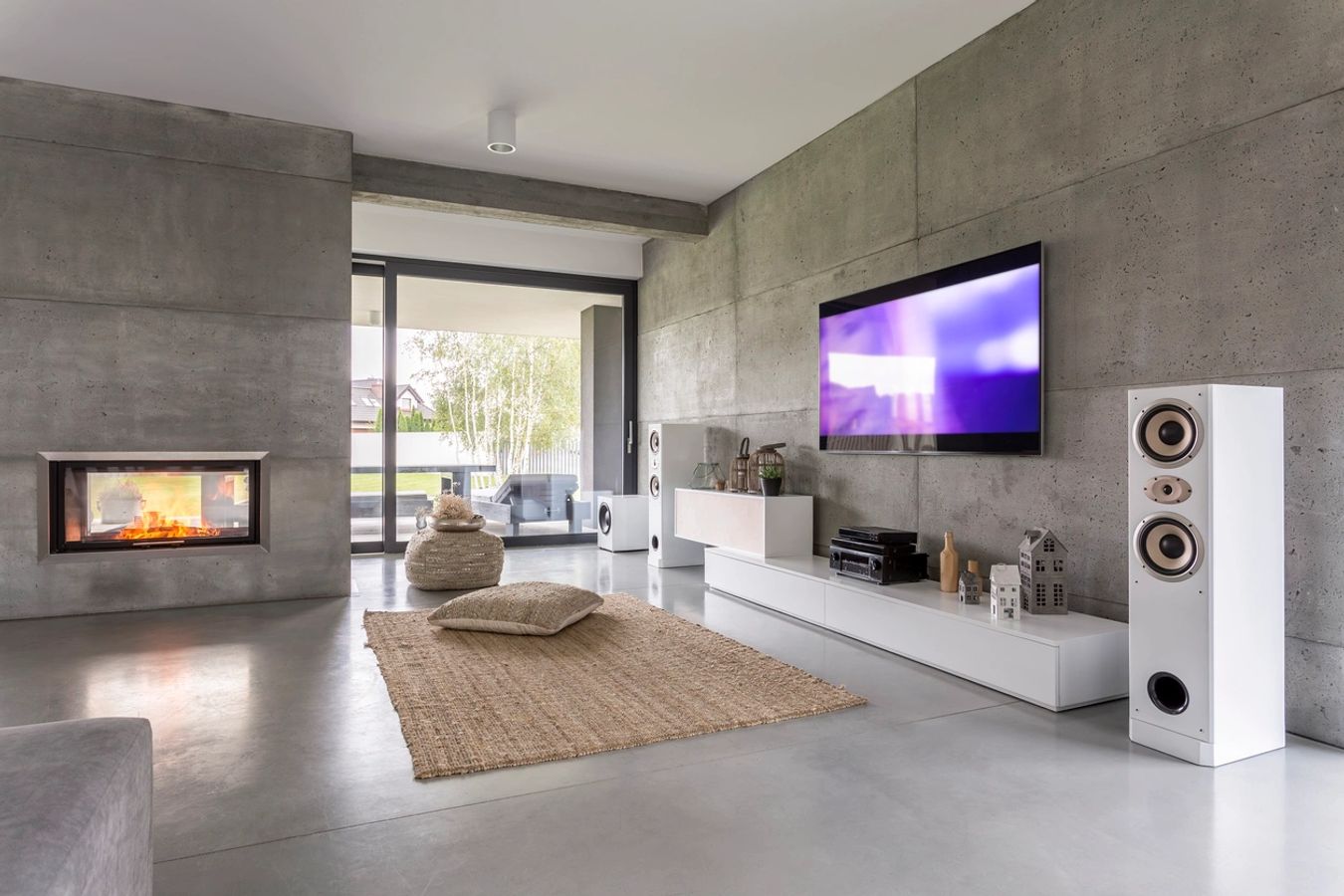 Modern living room with a wall-mounted TV, fireplace, and concrete walls